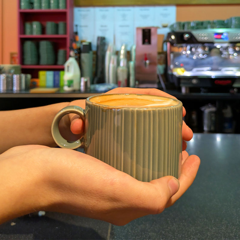 Cup of coffee held up by hands in The Lounge